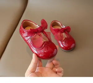 Detail of red patent leather girl's Mary Jane shoes with mesh bow and scalloped trim