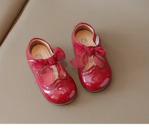 Top view of shiny burgundy patent leather kids shoes with mesh bow and floral punch details