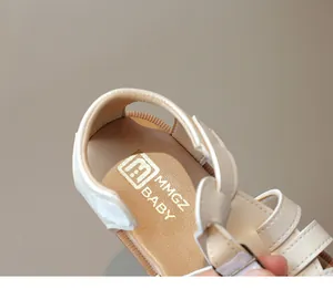 Macro shot of minimalist baby sandals showing the soft cushioned inner sole and brand logo