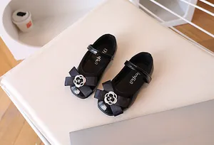 Detail of girls black patent Mary Jane shoes with camellia flower and ribbon bow