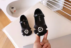 Detail of girls black patent leather Mary Jane shoes with satin bow and camellia flower