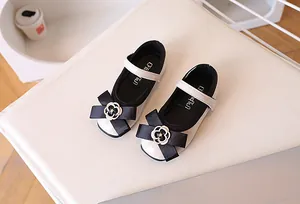 Detail of girls' Mary Jane leather shoes with black bow and camellia floral ornament