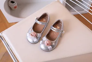 Detalle de zapatos plateados de princesa para niña con rosas rosas y perlas finas