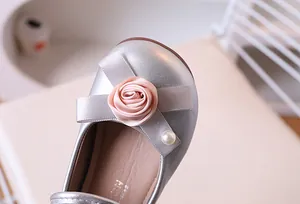 Detalle de zapatos Mary Jane plateados para niña con flor de satén rosa y perla