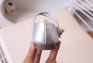 Detalle de zapato Mary Jane plateado con detalle de perla blanca y costura fina