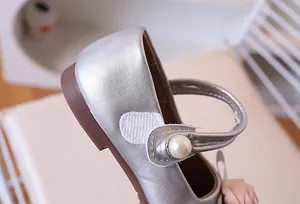 Detalle de zapato Mary Jane plateado con hebilla de perla y adorno floral rosa