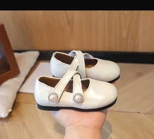 Detail von cremefarbenen Mary Jane Schuhen mit Perlen-Schnallen und Kreuzriemen