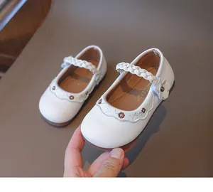 Detail von weißen Mädchen Mary Janes mit Blumenstickerei und gewebtem Riemendesign