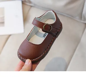 Détail de chaussures bébé en cuir marron foncé avec coutures contrastées et boucle en métal