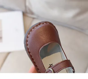 Gros plan de chaussures Mary Jane brunes avec coutures blanches et texture cuir grainé