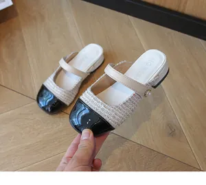 Detail of girls beige tweed and black leather Mary Jane slippers with a pearl buckle