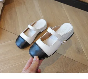 Detailed close-up of children's Mary Jane mule shoes with pearl buckles and black toe cap