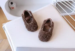 Detail von warmen braunen Plüsch-Slippern für Kinder mit lockiger Kunstfell-Struktur