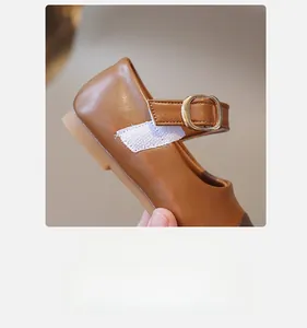 Detail of kids brown Mary Jane shoes featuring velcro strap and metallic buckle