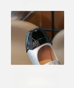 Dettaglio di scarpa Mary Jane argento con punta in vernice nera e decorazione di rosa elegante