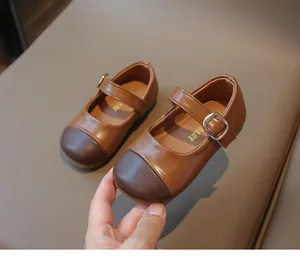 Detail of children's Mary Jane leather shoes with contrast brown colors and metal buckle