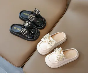 Close-up of girls' patent leather mule shoes featuring large bows with pearls and rhinestones