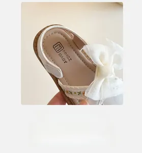 Gros plan d'une sandale pour fille avec broderie florale et nœud en organza blanc