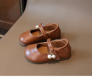 Detailed close-up of girls' brown leather Mary Jane shoes with elegant pearl ornaments