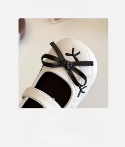 Close-up of girls white quilted shoes with black bow and spacious round toe detail