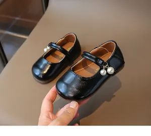 Detail of black patent leather Mary Jane shoes for girls with elegant pearl charms