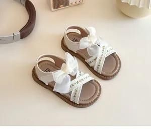 Détail de sandales pour filles avec nœud en tulle crème et broderies florales colorées