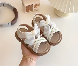 Détail de sandales beiges pour filles avec grand nœud en organza et broderie florale