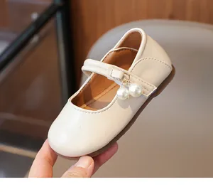 Close-up of girls beige Mary Jane shoes with elegant pearl charms and non-slip rubber soles