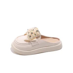 Girl's cream leather mules with oversized pearl bow and thick sole on white background