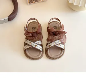Détail de sandales pour filles avec broderie florale et grand nœud en tulle