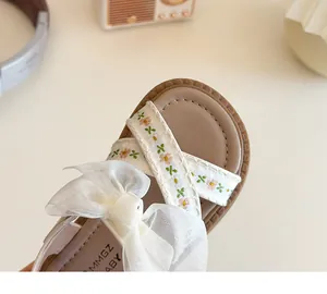Détail d'une sandale pour fille avec broderie florale et nœud en tulle décoratif