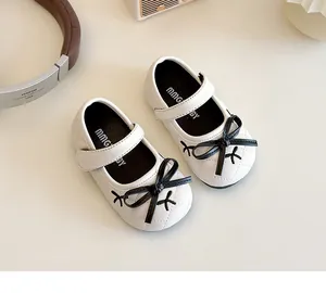 Detail of white toddlers princess shoes with quilted faux leather and a black bow