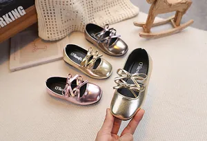 Dettaglio delle scarpe Mary Jane da bambina con fiocco in oro, argento e oro rosa