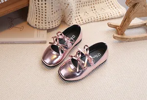 Dettaglio di scarpe Mary Jane rosa metallizzato per bambina con doppi fiocchi su tappeto