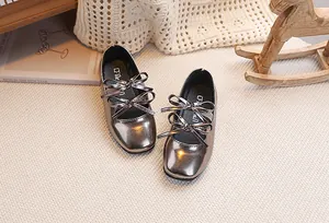 Dettaglio di scarpe Mary Jane metallizzate con doppio fiocco in un ambiente accogliente