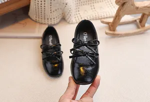 Dettaglio delle scarpe Mary Jane in vernice nera per bambina con graziosi fiocchi decorativi