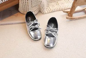 Dettaglio di scarpe in vernice argento per bambine con doppio fiocco e finitura metallica