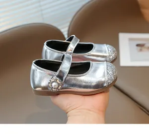 Detailed macro of silver glitter girls Mary Jane shoe with pearl floral buckle and anti-slip sole