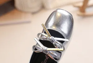 Dettaglio di scarpe Mary Jane argento metallizzato per bambina con doppio fiocco