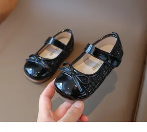 Detail of girls' black tweed Mary Jane shoes with patent leather bow and non-slip sole