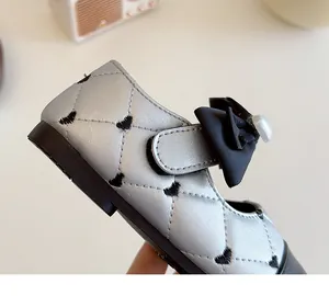 Detail van zilveren Mary Jane meisjesschoen met hartborduurwerk en parelstriklus