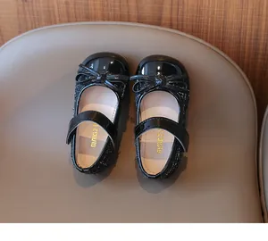 Detail of girls' black tweed Mary Jane shoes with patent leather toe and bow accent