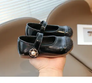 Macro view of girls' black patent Mary Janes with glitter toe and pearl flower buckle