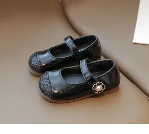 Detail of girls' black patent Mary Janes with glitter toe and pearl flower buckle