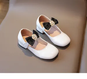 Detailansicht der weißen Mädchen Lackschuhe mit schwarzer Schleife und Kamelien-Anhänger