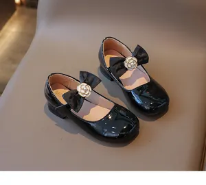 Detail von Mädchen Mary Janes aus schwarzem Lackleder mit Schleife und Kamelie