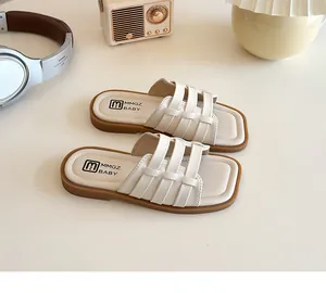Vue à plat de sandales enfant tressées crème sur un bureau beige avec décors