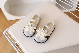 Dettaglio di scarpe casual da bambina con fiocco in pizzo e chiusura a cinturino