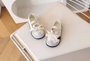 Vista dall'alto di scarpe per bambine con fiocco in pizzo crema e grigio e cinturino elastico