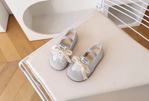 Dettaglio di scarpe Mary Jane grigio-blu per bambine con grande fiocco in pizzo ed elastico